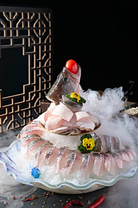 布满碎冰的青色瓷盘装的海鲈鱼刺身生鱼片