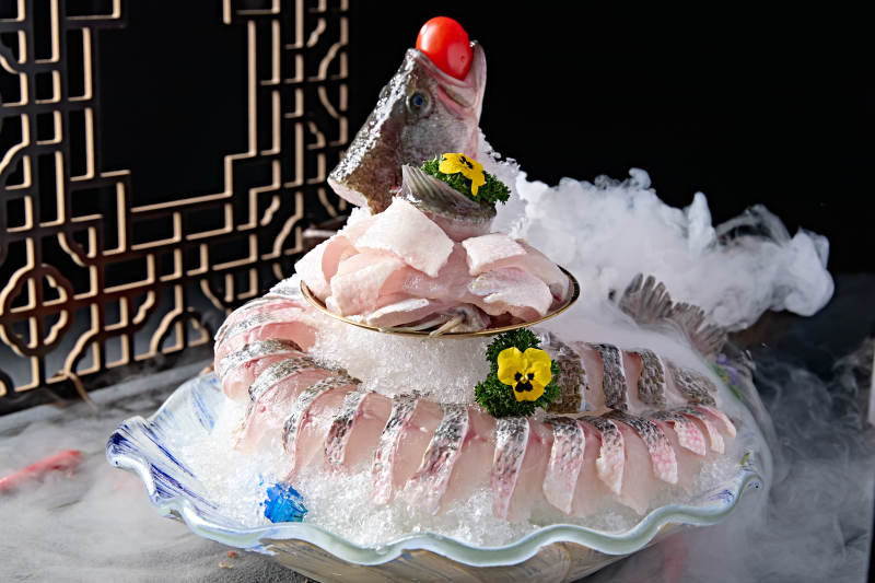 布满碎冰的青色瓷盘装的海鲈鱼刺身生鱼片