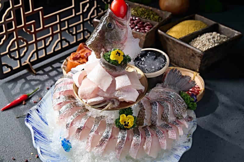 布满碎冰的青色瓷盘装的海鲈鱼刺身生鱼片