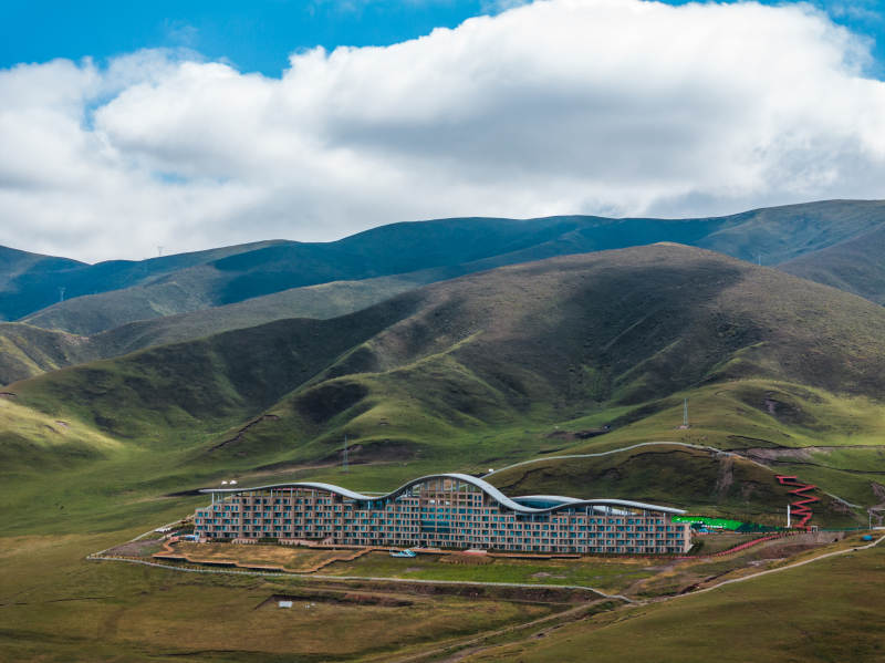 草原上现代建筑与连绵山脉蓝天白云自然景观