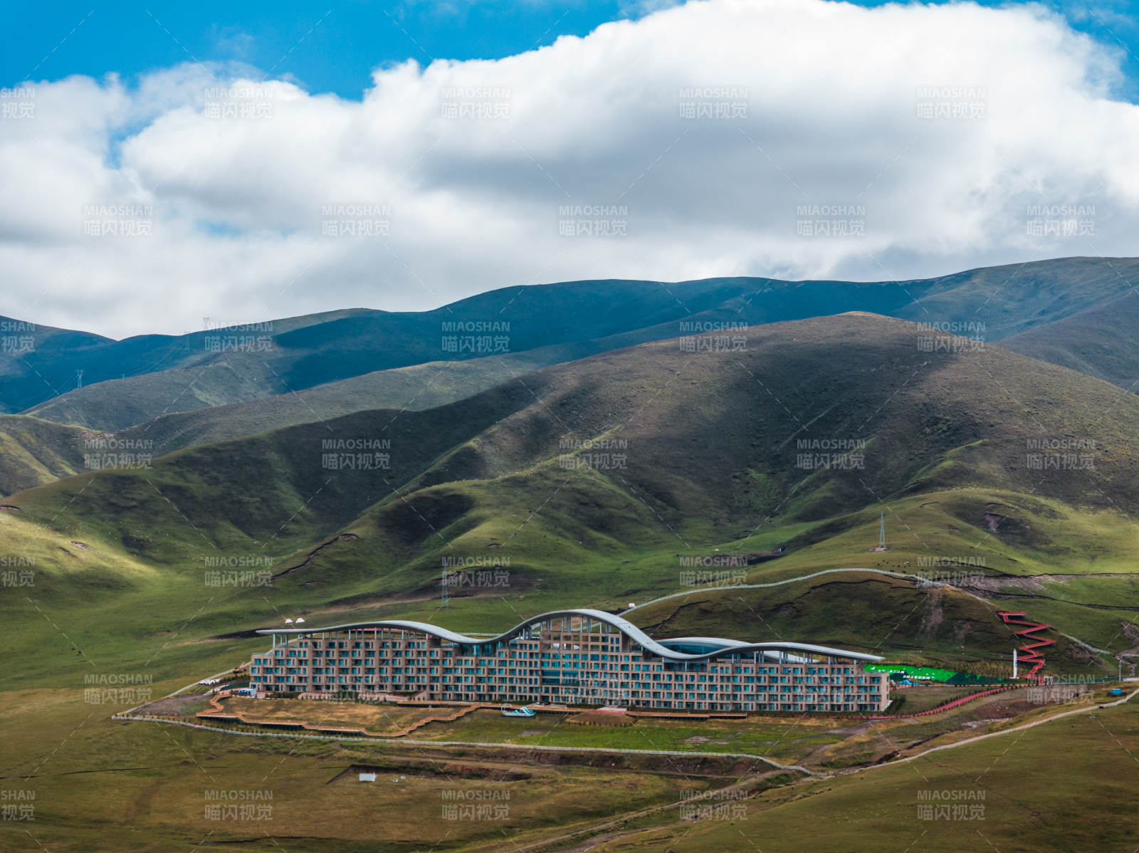 草原上现代建筑与连绵山脉蓝天白云自然景观