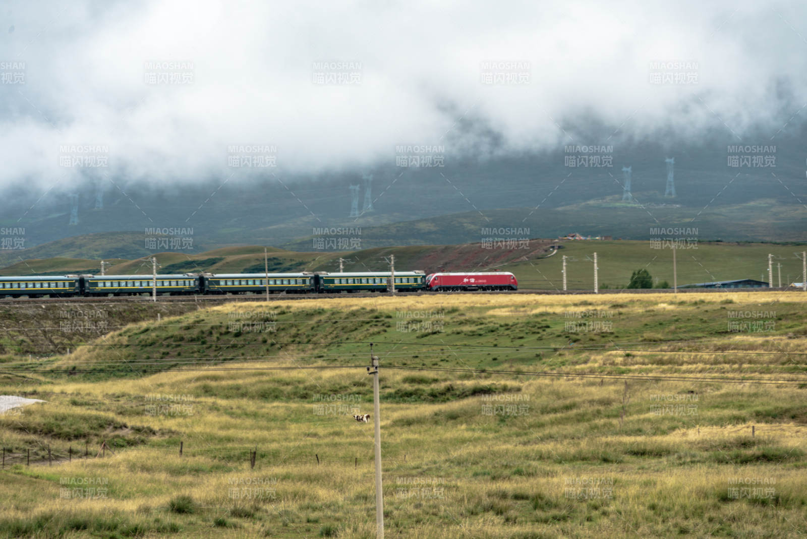 草原铁路上红色列车穿过云雾驶过高原山峦间