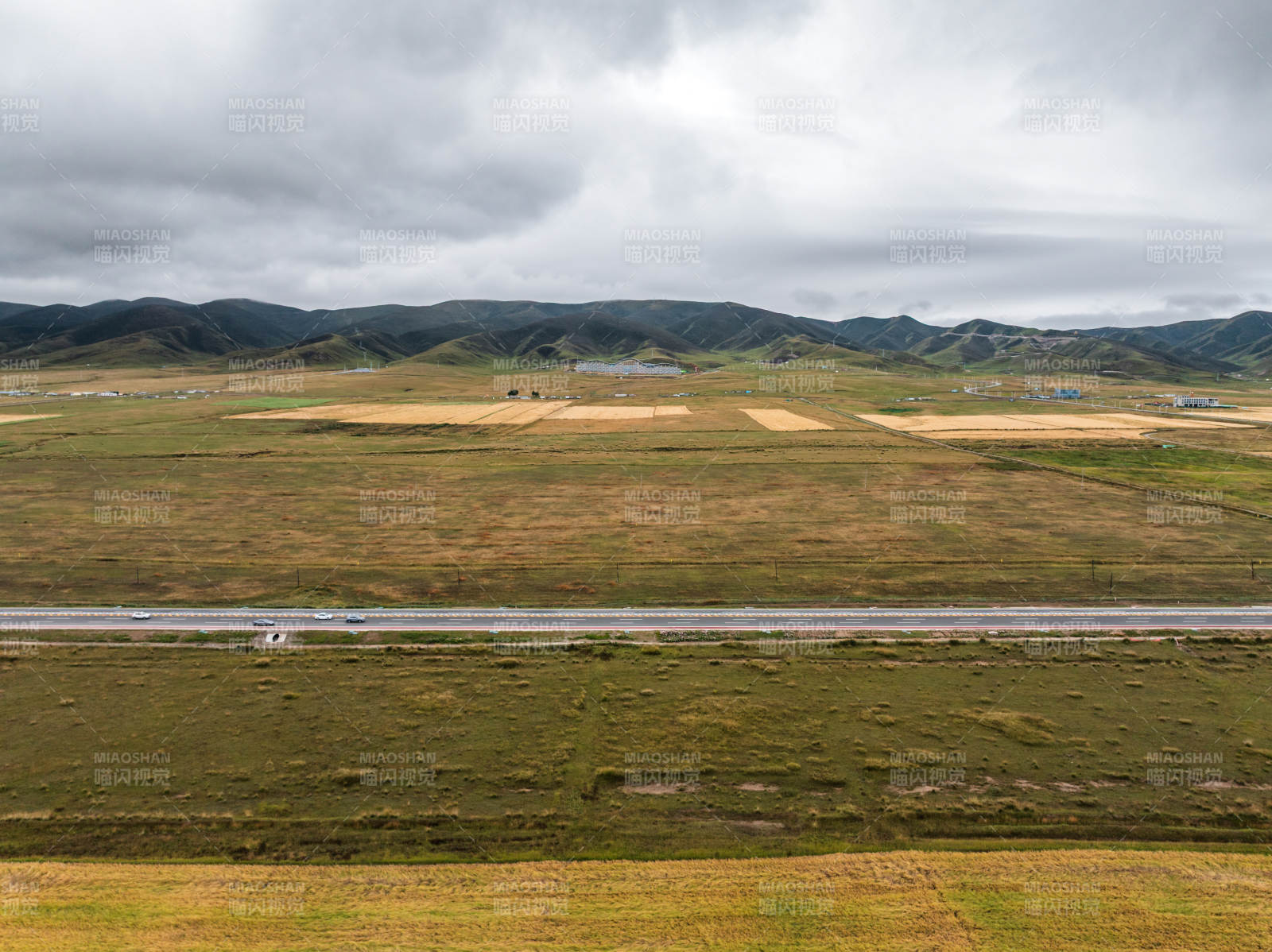 草原蜿蜒公路远景山脉农田自然风光阴云密布