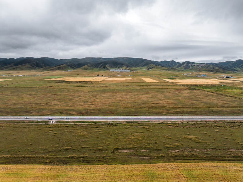 草原蜿蜒公路远景山脉农田自然风光阴云密布