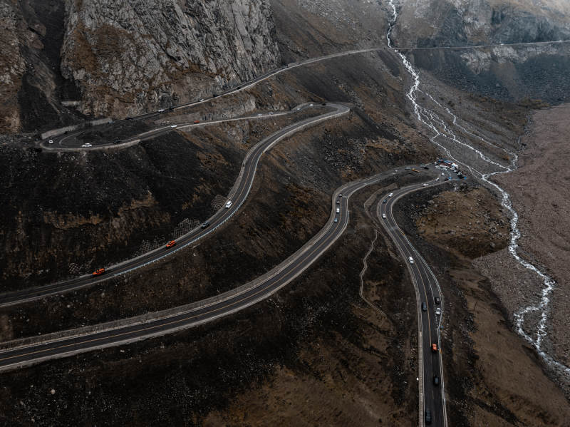 俯拍蜿蜒公路穿行岩壁河床的荒凉山地景致