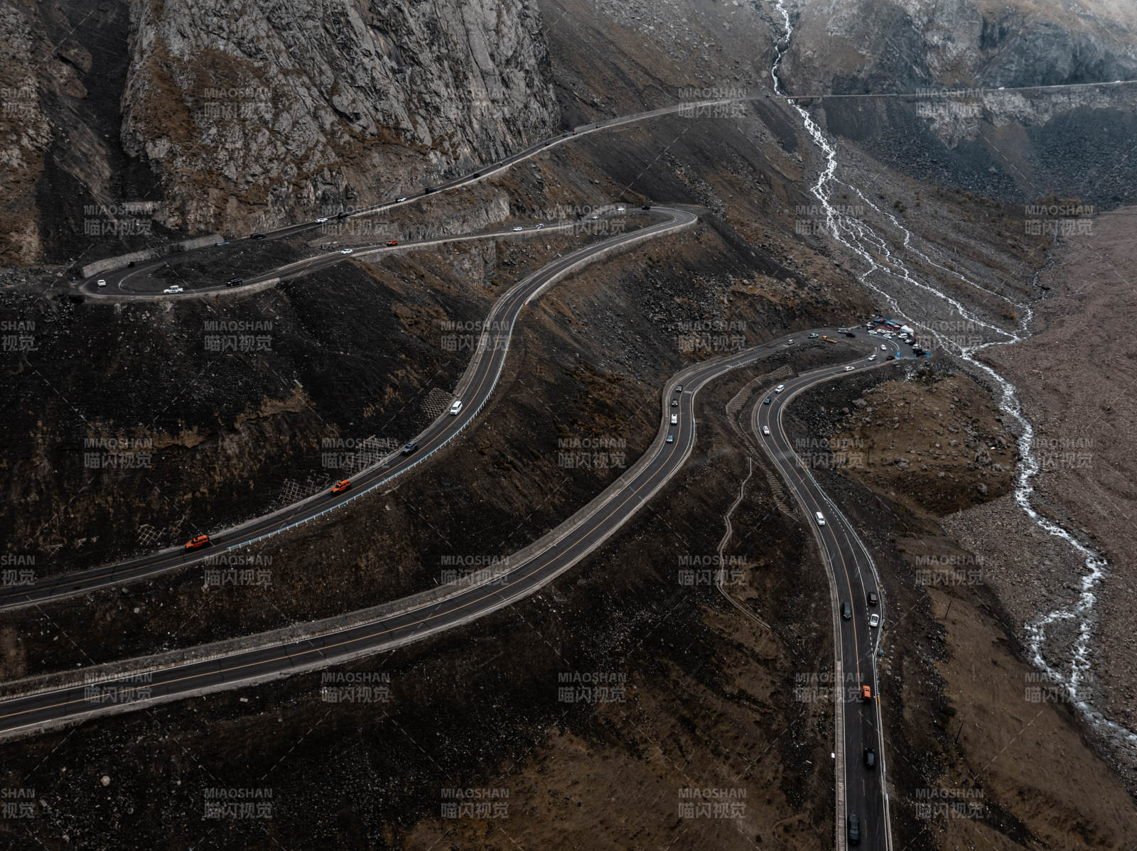 俯拍蜿蜒公路穿行岩壁河床的荒凉山地景致