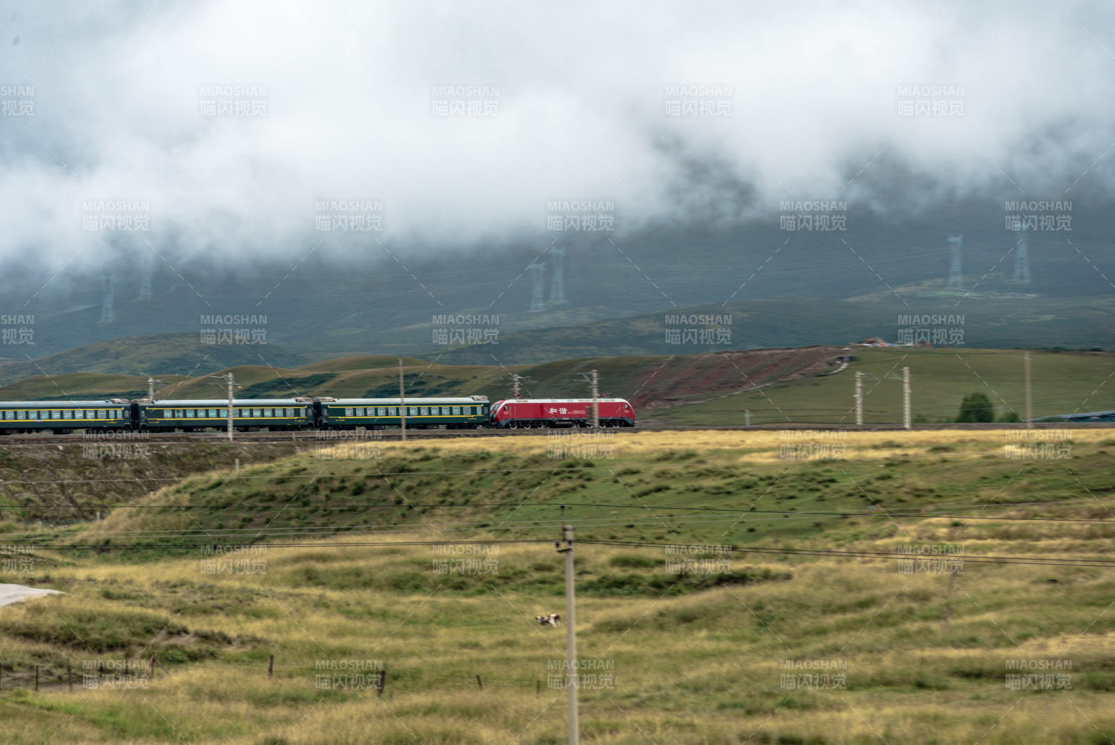 高山草原上和谐号机车牵引绿皮火车穿云行驶