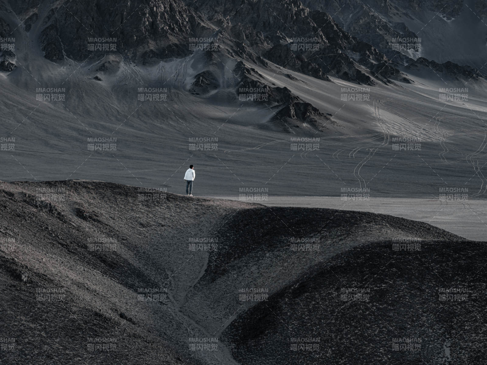 孤独旅人站立在荒凉山地眺望探索远方沙漠