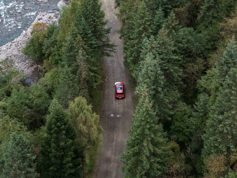 红色汽车在山林溪流边穿越原始森林越野自驾