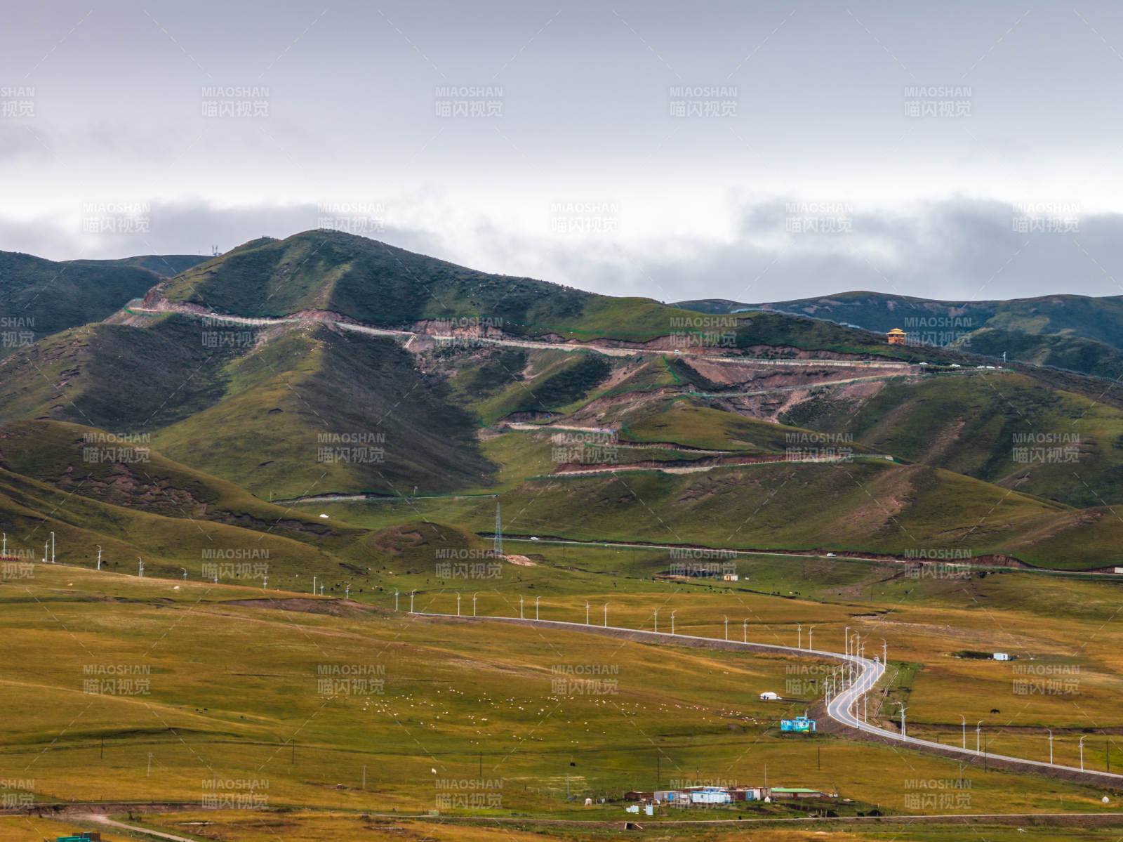 蜿蜒公路穿过草原山地远方山腰牧群自然景观