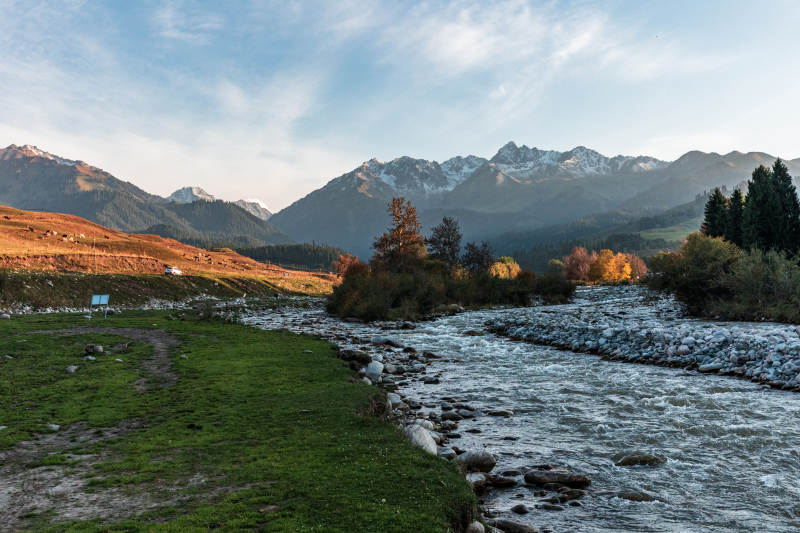 新疆恰西草原雪山脚下山间溪流草甸太阳照耀