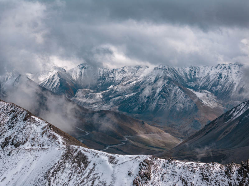 雪山云海间蜿蜒公路展现自然壮美与高原云雾