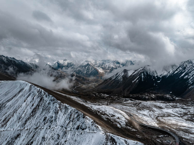 雪山云雾缭绕下蜿蜒道路点缀的高山壮丽景观