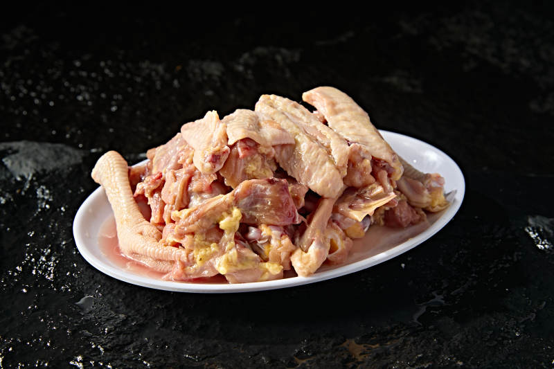 摆放在白色背景上分切好的生鲜鸡肉