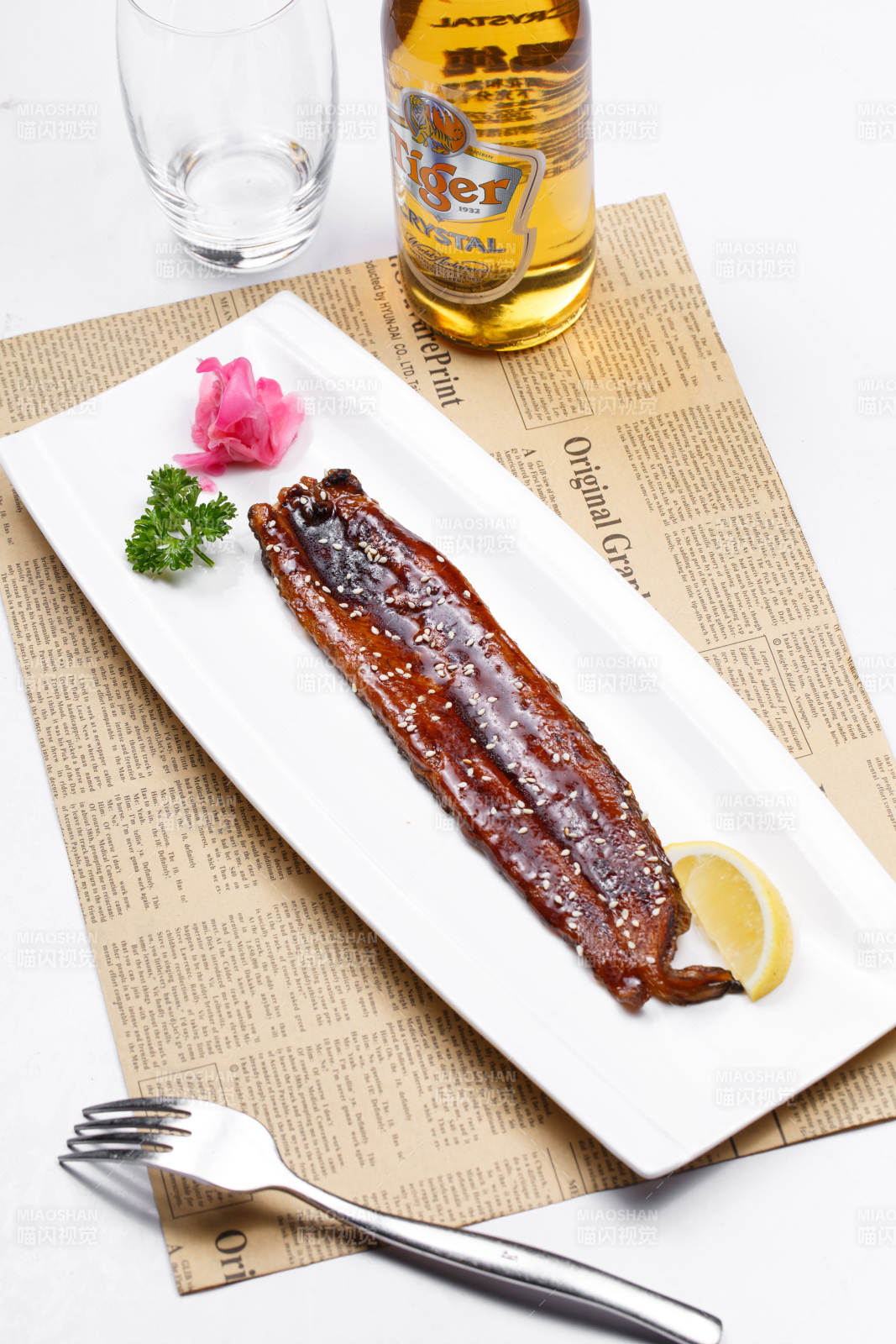 长方形瓷盘装的日式烤鳗鱼摆放在英文包装纸上