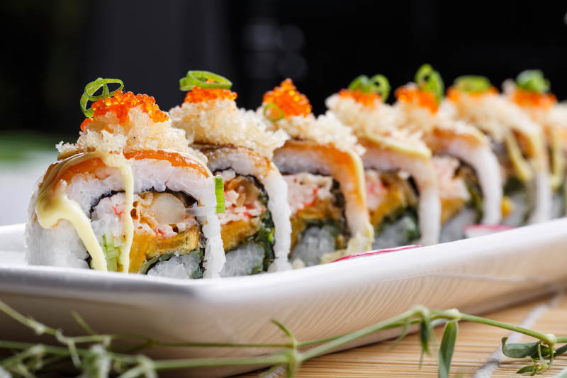 长瓷盘装的蟹籽教授卷摆放在寿司帘上