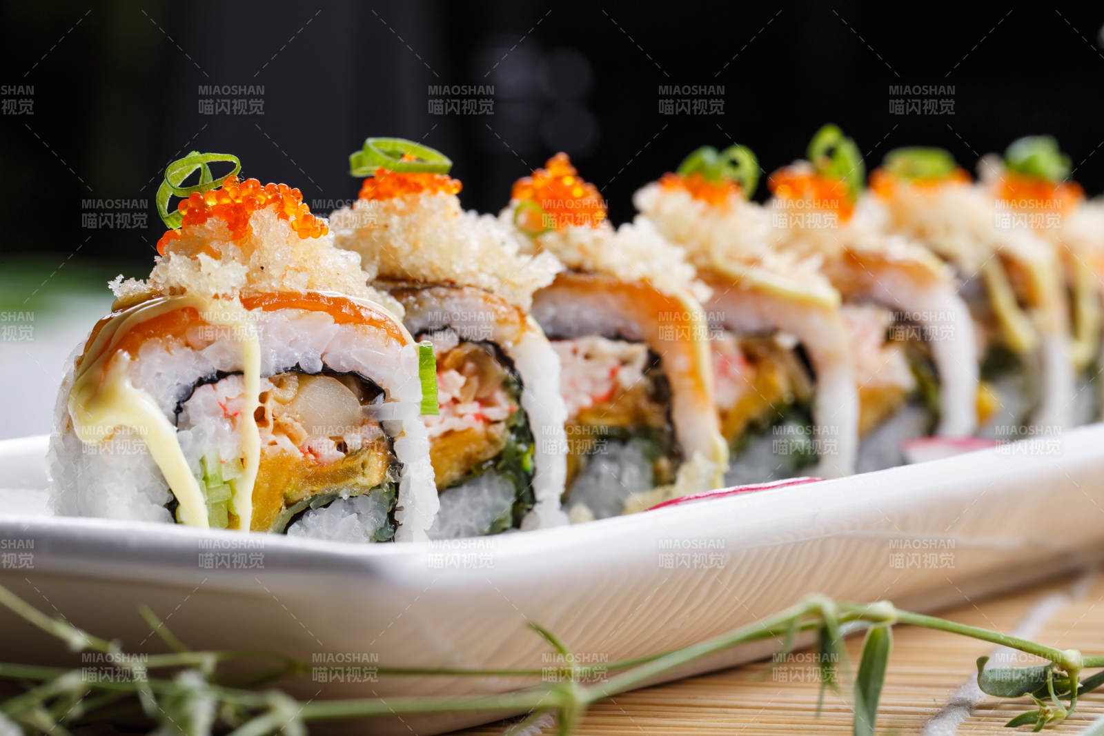 长瓷盘装的蟹籽教授卷摆放在寿司帘上