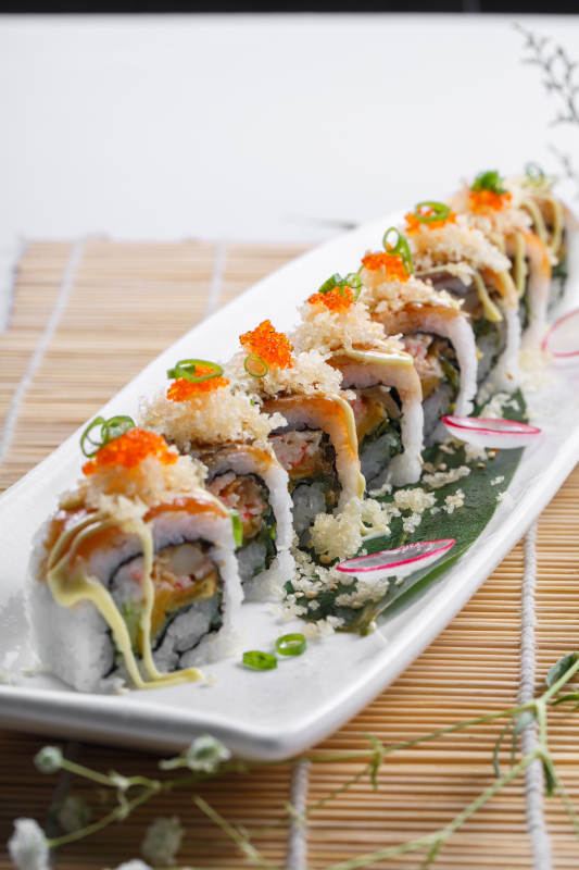 长瓷盘装的蟹籽教授卷摆放在寿司帘上