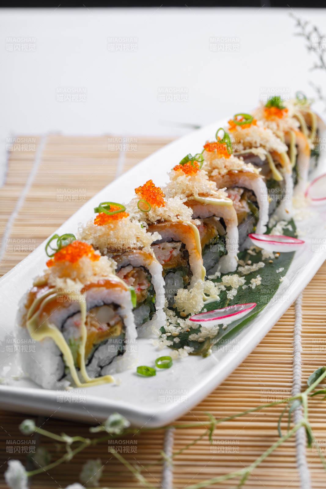长瓷盘装的蟹籽教授卷摆放在寿司帘上