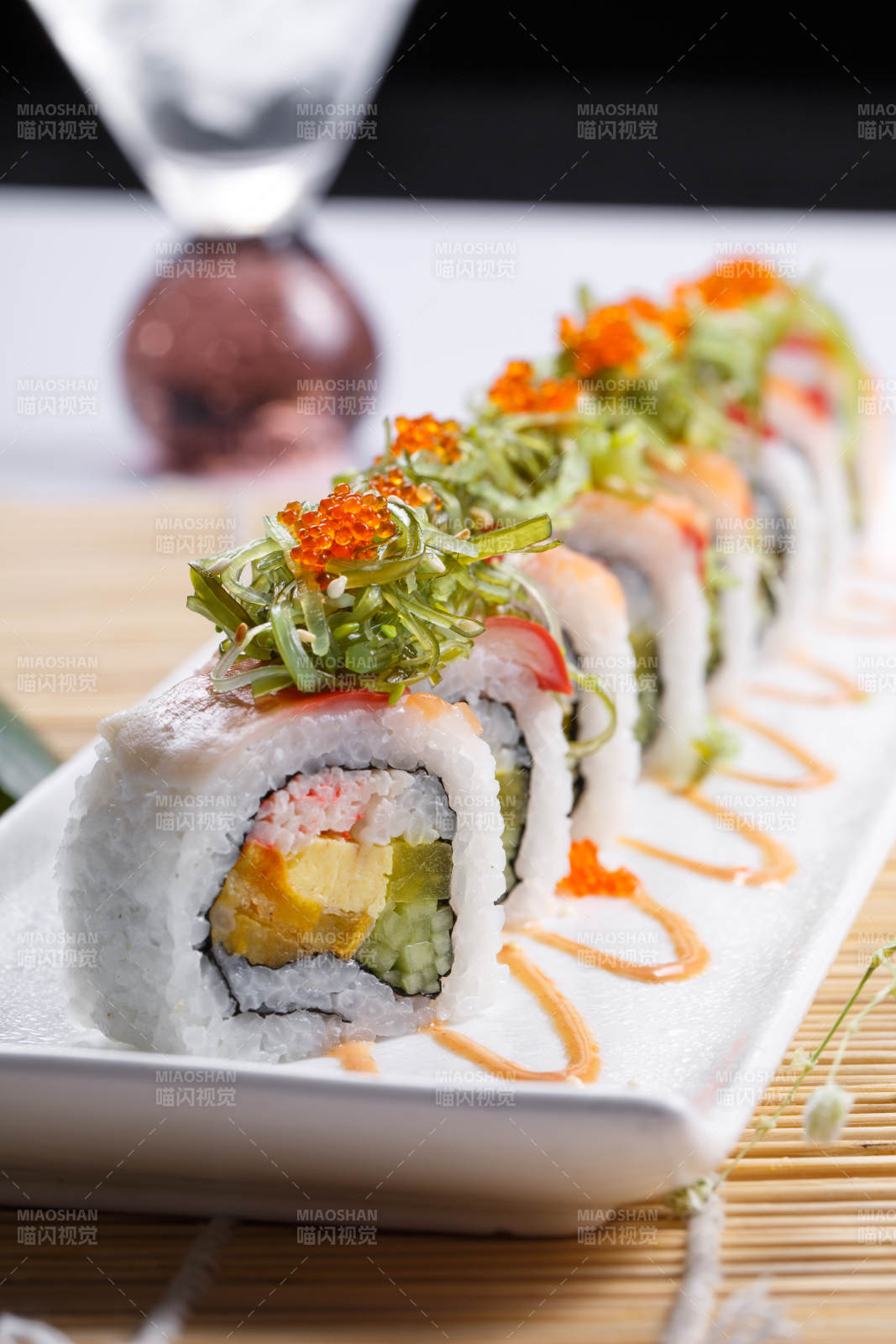 长瓷盘装的蟹籽教授卷摆放在寿司帘上