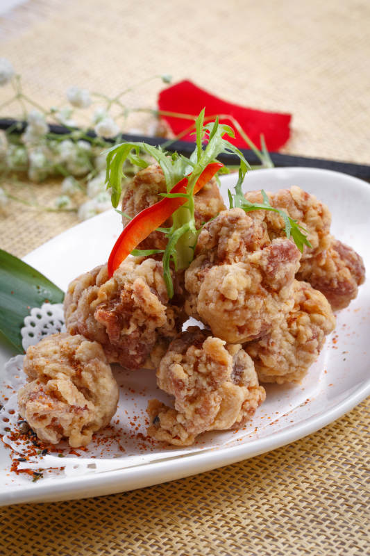 鹅颈瓷盘装的炸鸡块摆放在草垫上