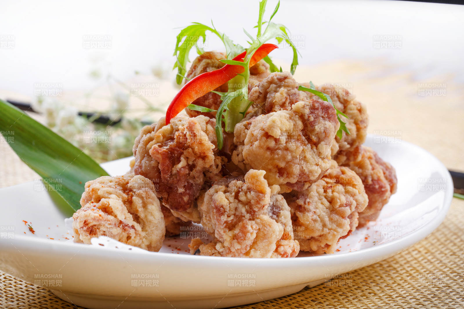 鹅颈瓷盘装的炸鸡块摆放在草垫上