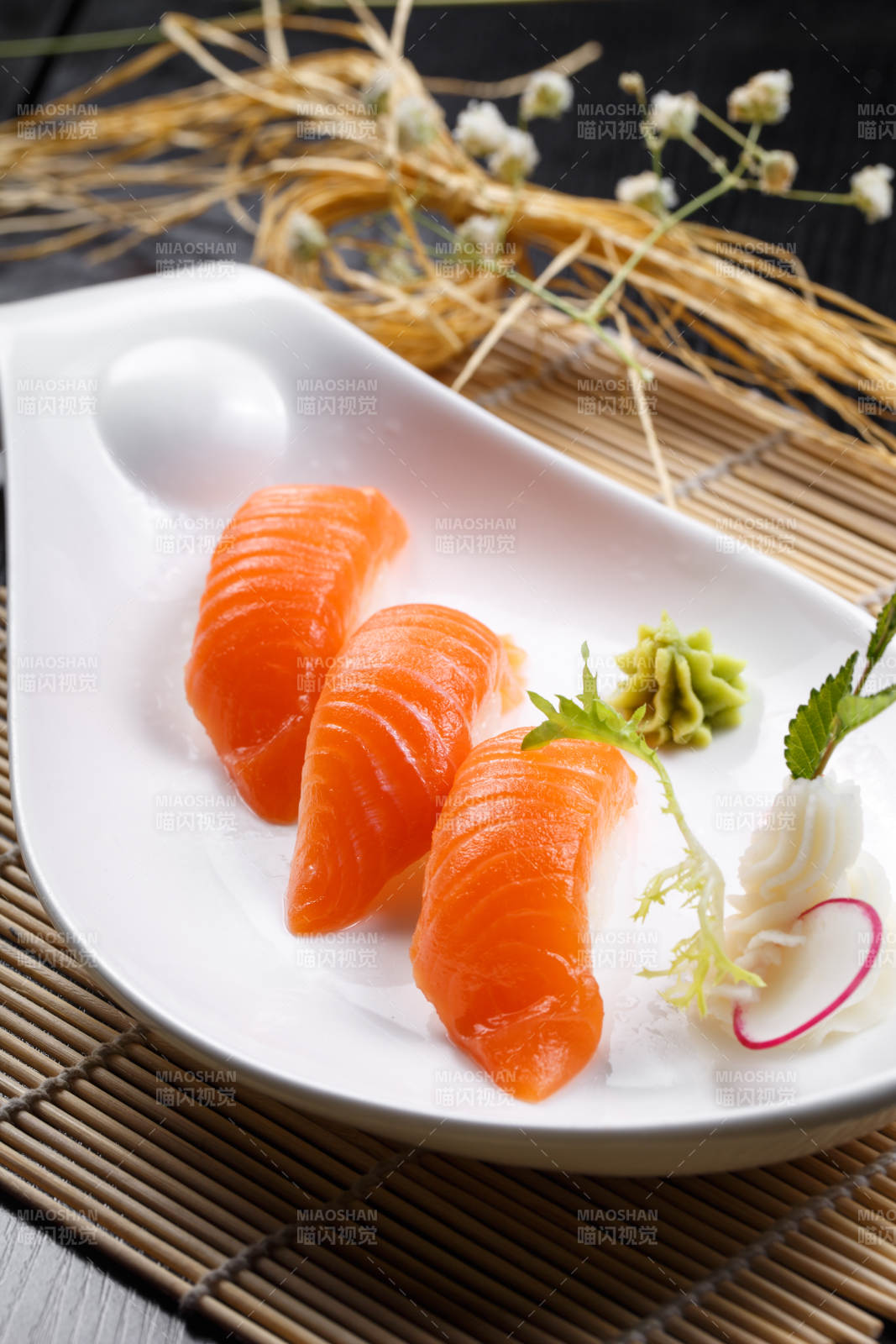 三文鱼手握寿司摆放在寿司帘上图片