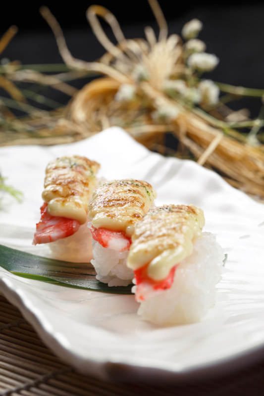 芝士焗蟹钳肉手握寿司摆放在寿司帘上