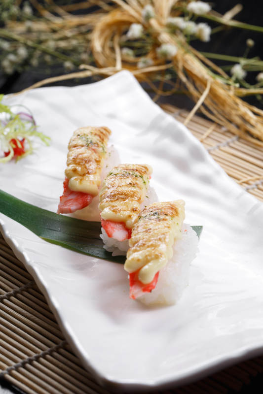 芝士焗蟹钳肉手握寿司摆放在寿司帘上