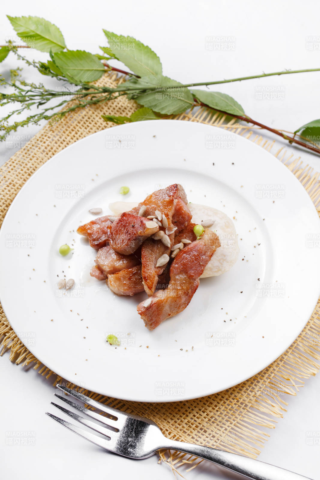 圓形白瓷盤裝的鐵板煎牛腹肉擺放在草墊上
