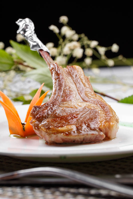 圆形白瓷盘装的波尔多法式铁板羊排摆放在餐垫上