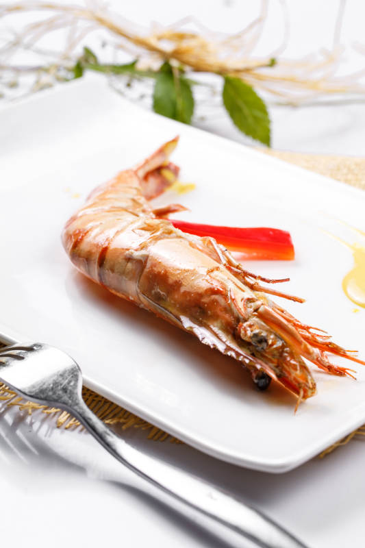 长方形瓷盘装的铁板野生明虾皇摆放在草垫上