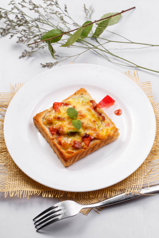 白色圆盘装现烤海鲜牛肉小披萨摆放在草垫上