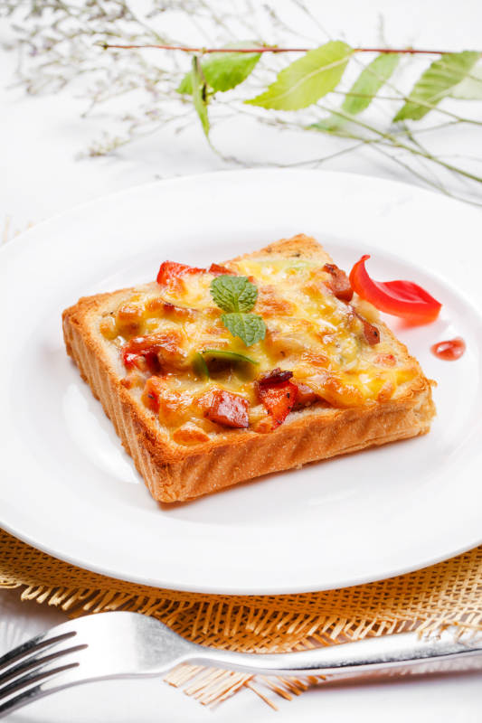 白色圆盘装现烤海鲜牛肉小披萨摆放在草垫上