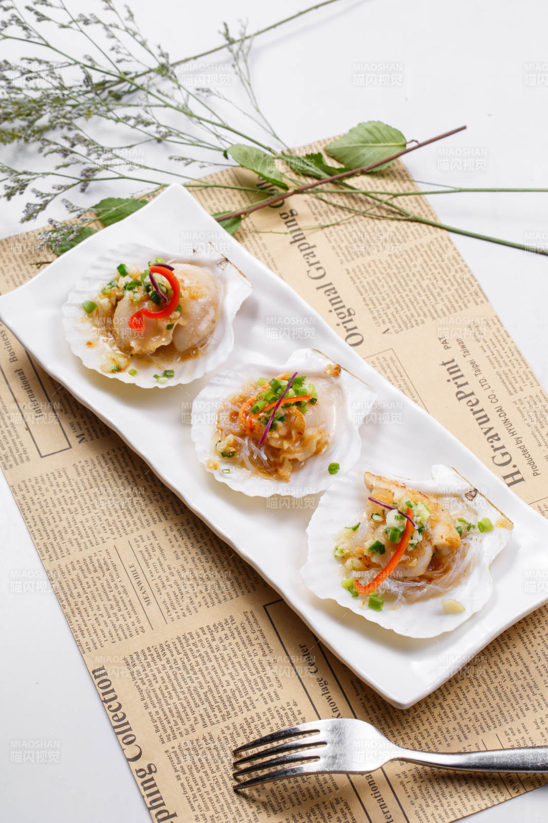 蒜蓉粉丝XO酱蒸扇贝摆放在英文包装纸上图片