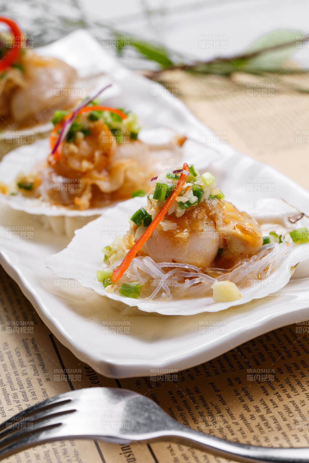 蒜蓉粉丝XO酱蒸扇贝摆放在英文包装纸上图片