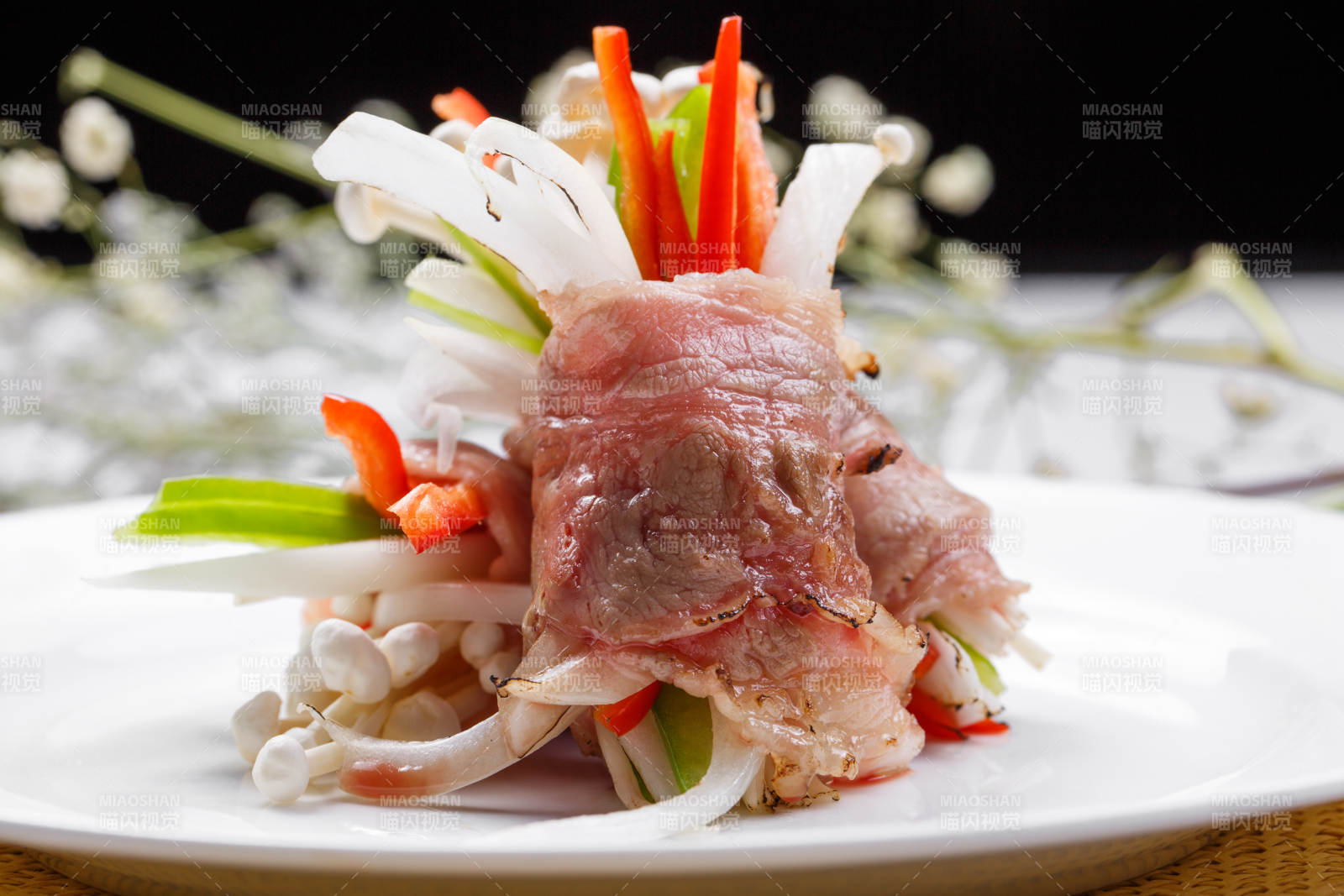 白色圆盘装的法式鹅肝牛肉卷摆放在草垫上