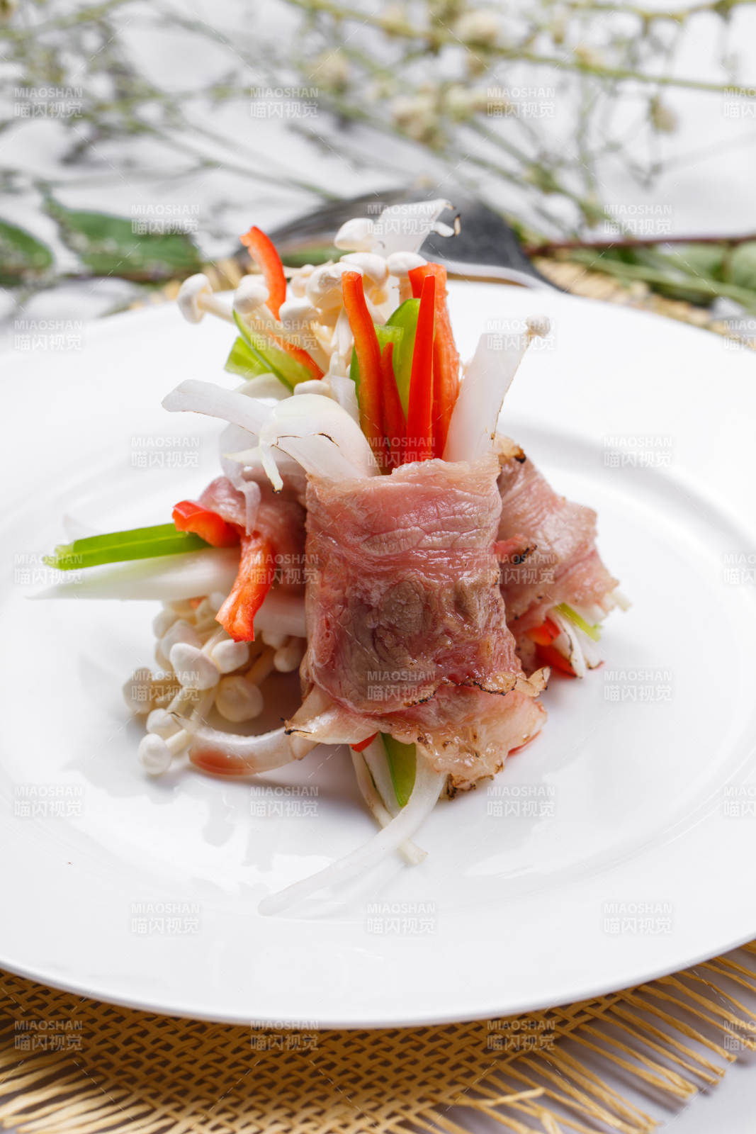 白色圆盘装的法式鹅肝牛肉卷摆放在草垫上