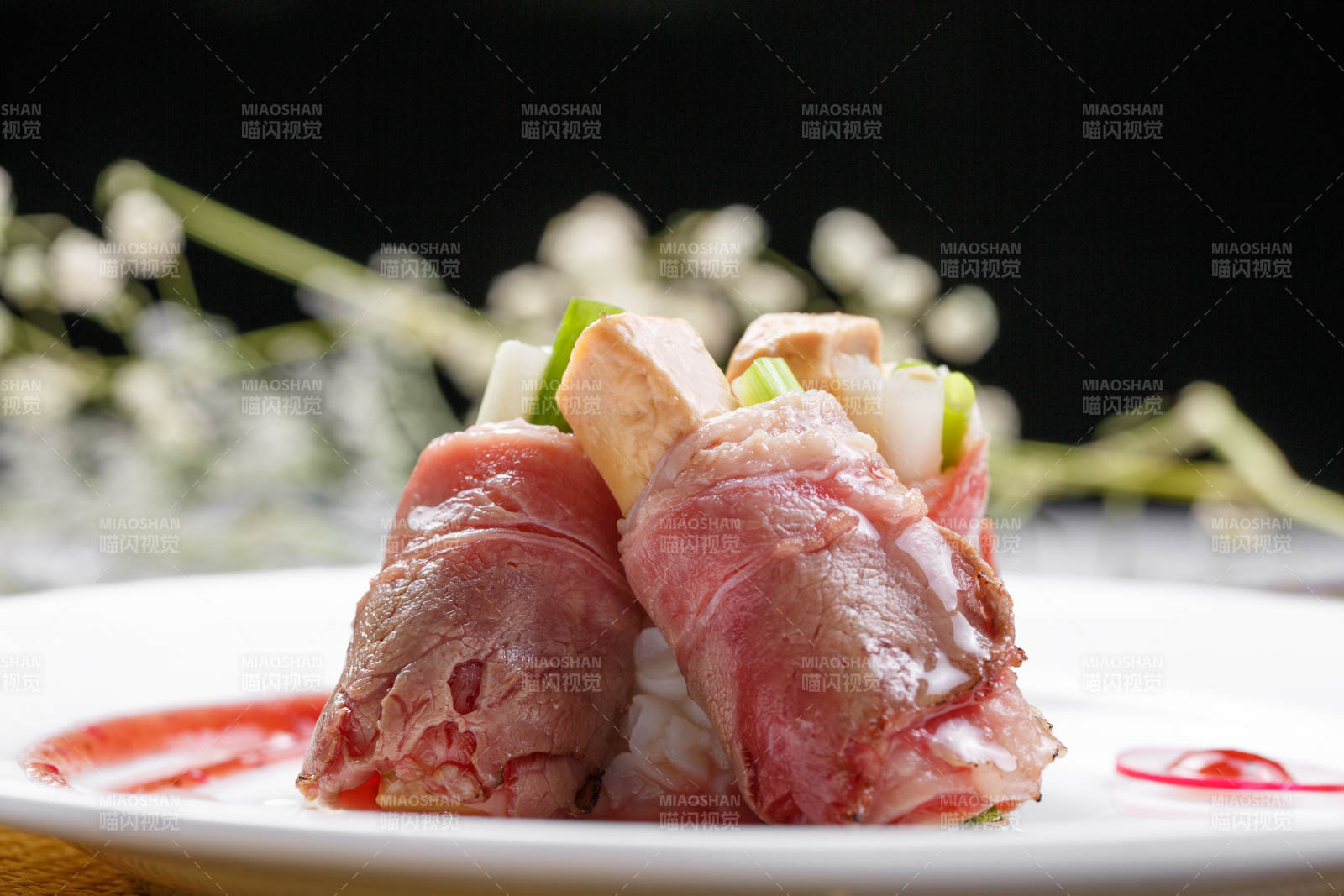 白色圆盘装的法式鹅肝牛肉卷摆放在草垫上