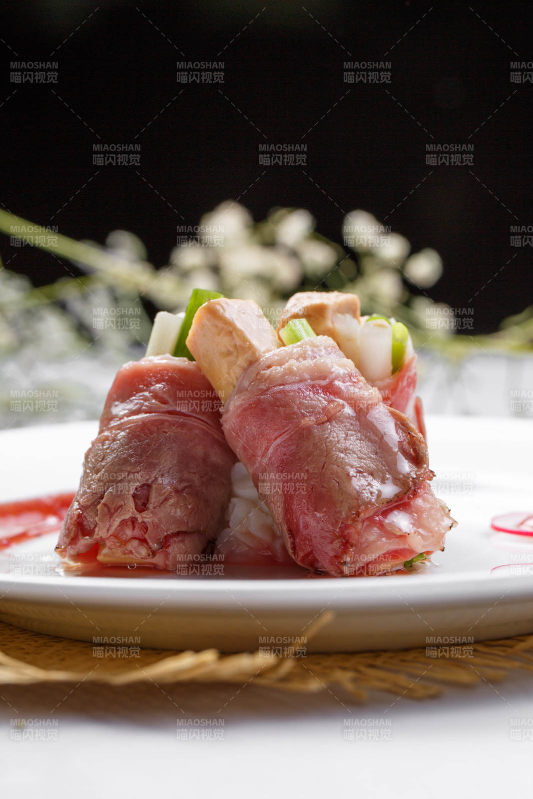 白色圆盘装的法式鹅肝牛肉卷摆放在草垫上