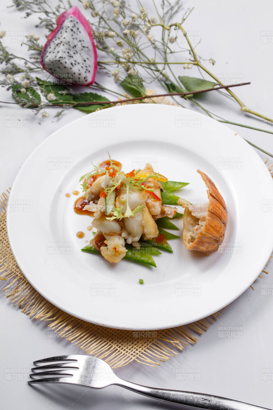 香辣铁板煎龙虾尾肉摆放在草垫上图片