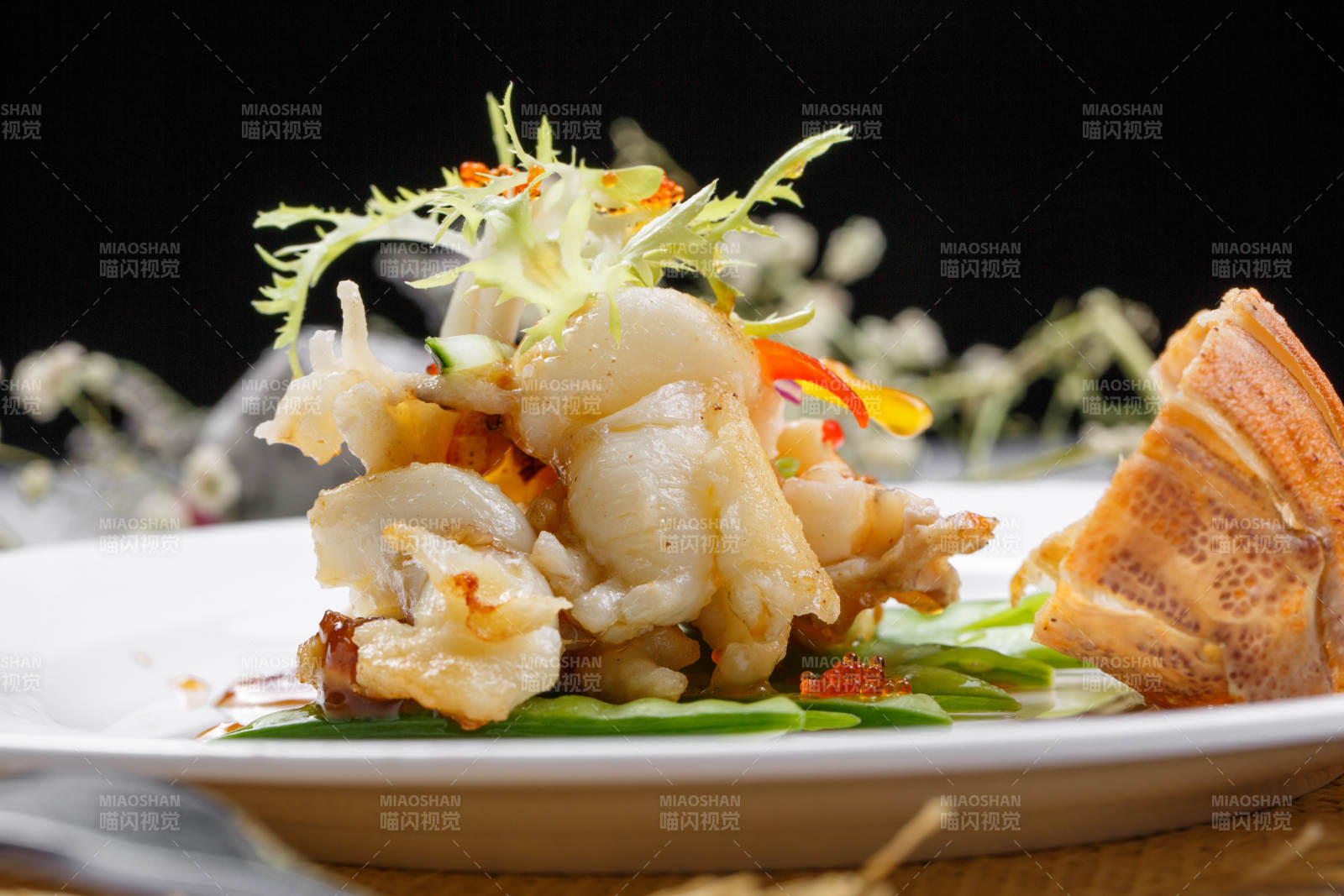 香辣铁板煎龙虾尾肉摆放在草垫上图片