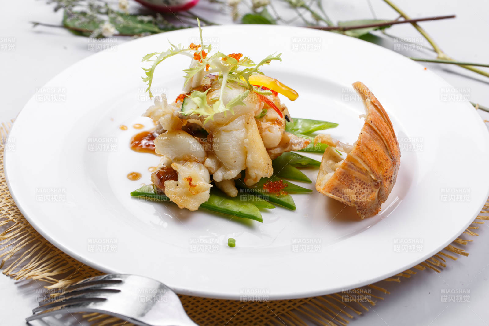 香辣铁板煎龙虾尾肉摆放在草垫上图片