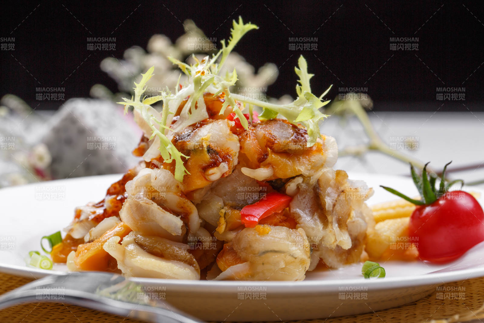 白色瓷盘装的铁板香辣扇贝肉摆放在草垫上