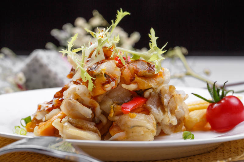 白色瓷盘装的铁板香辣扇贝肉摆放在草垫上