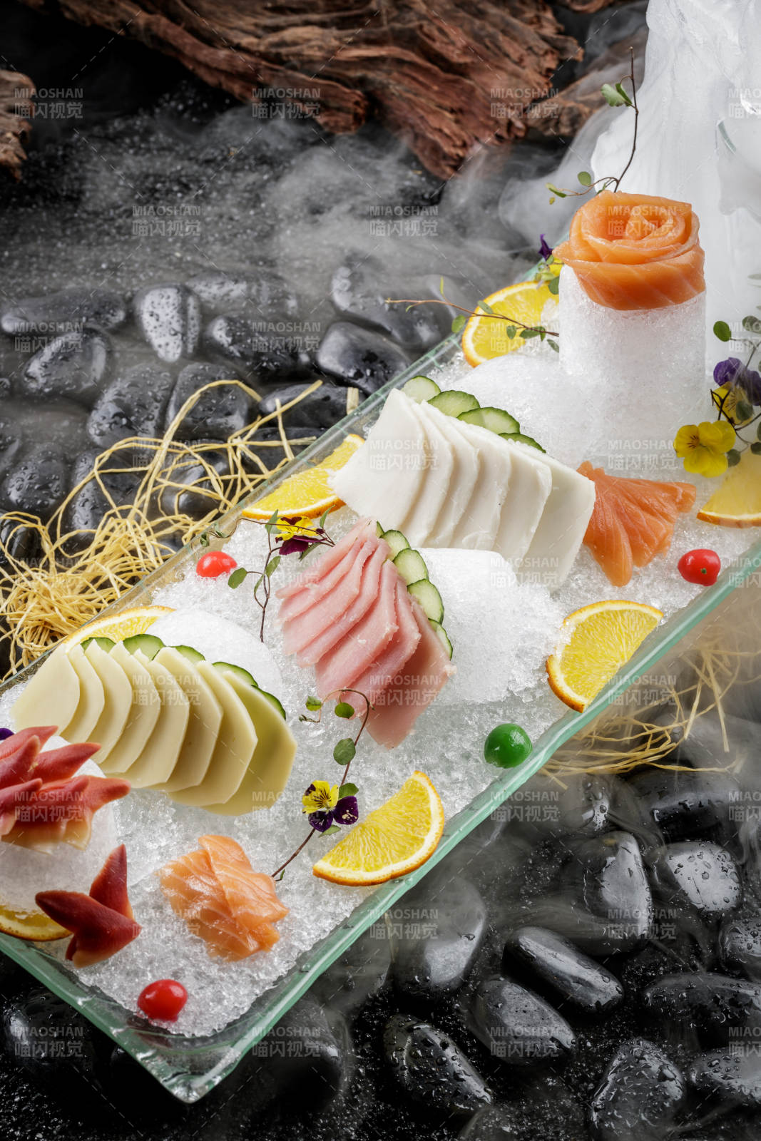 刺身拼摆放在干冰缭绕的黑色鹅卵石上