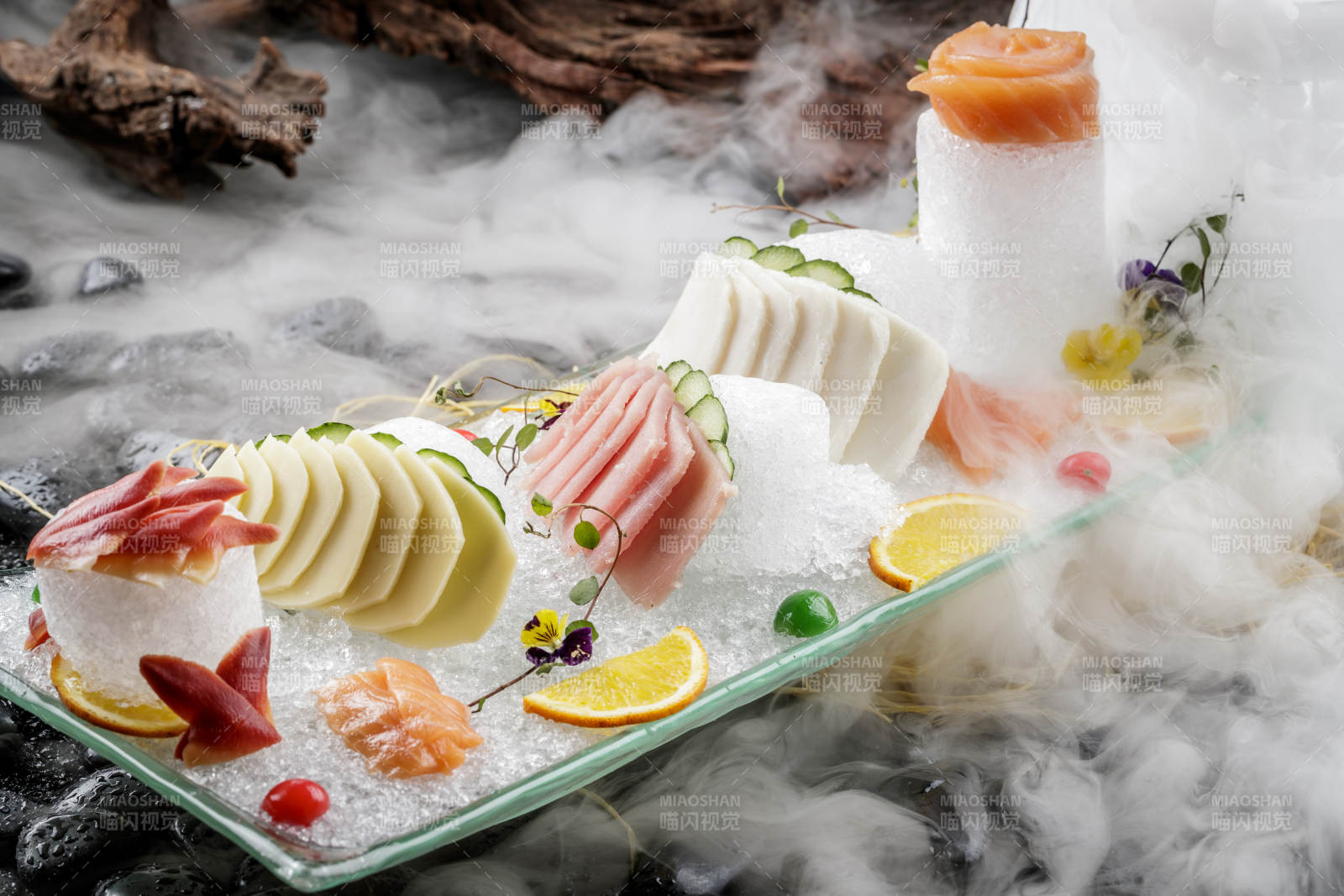 刺身拼摆放在干冰缭绕的黑色鹅卵石上