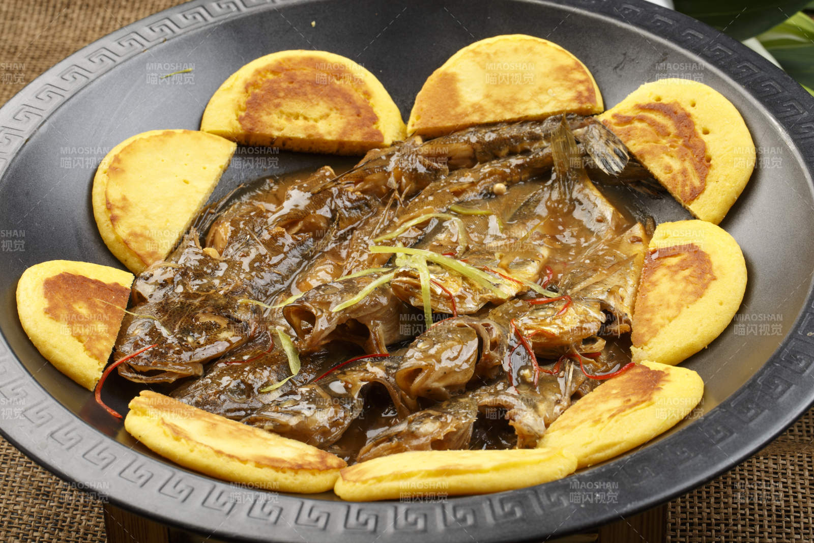 黑色铁锅装的垮炖海鲜杂鱼贴饼子