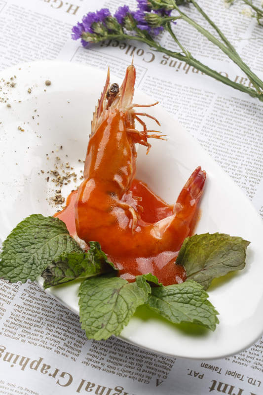 白色椭圆瓷盘装的浇汁大明虾