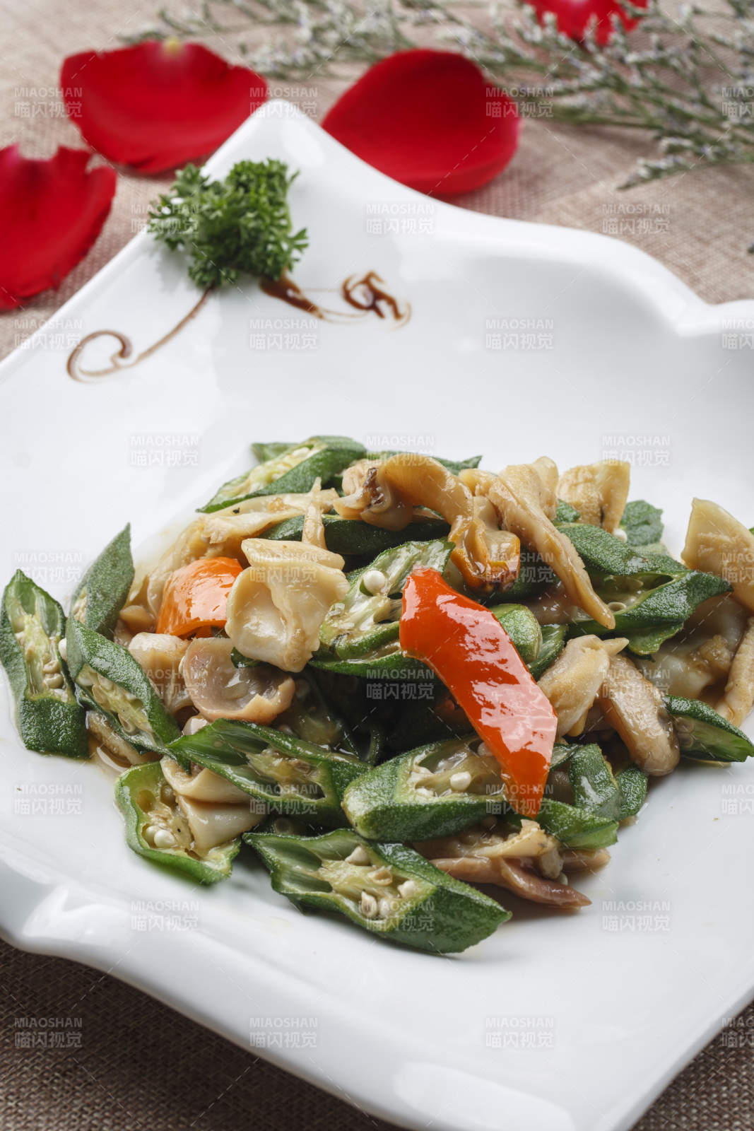 方形浪花边白瓷盘装的海鲜秋葵炒大海螺肉